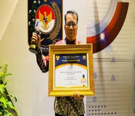 Kadisdukcapil Bengkalis, Ismail saat menerima penghargaan.(foto: zulkarnaen/halloriau.com)