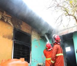 Petugas Damkar melakukan memadamkan api yang melahap rumah warga Dumai
