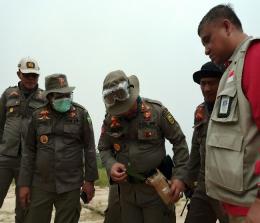 Anggota Satpol PP Provinsi Riau menunjukkan benda diduga bom molotov ditemukan di sisa karhutla.