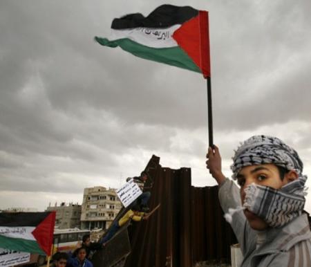 Seorang anak kecil mengibarkan bendera Palestina. 