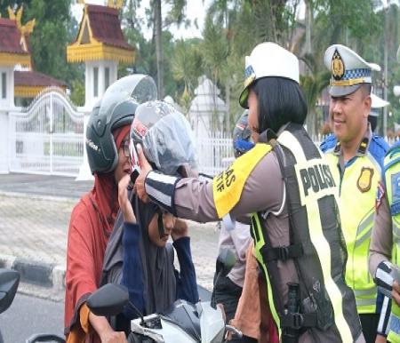 Kasat Lantas Kompol Birgitta Atvina Wijayanti memberikan helm ke anak pengendara motor (foto/int)